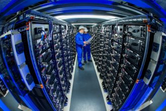 Trainees check the connections a row of power storage units in a commercial battery facility in Schwerin, Germany. Credit: Jens Büttner/picture alliance via Getty Images