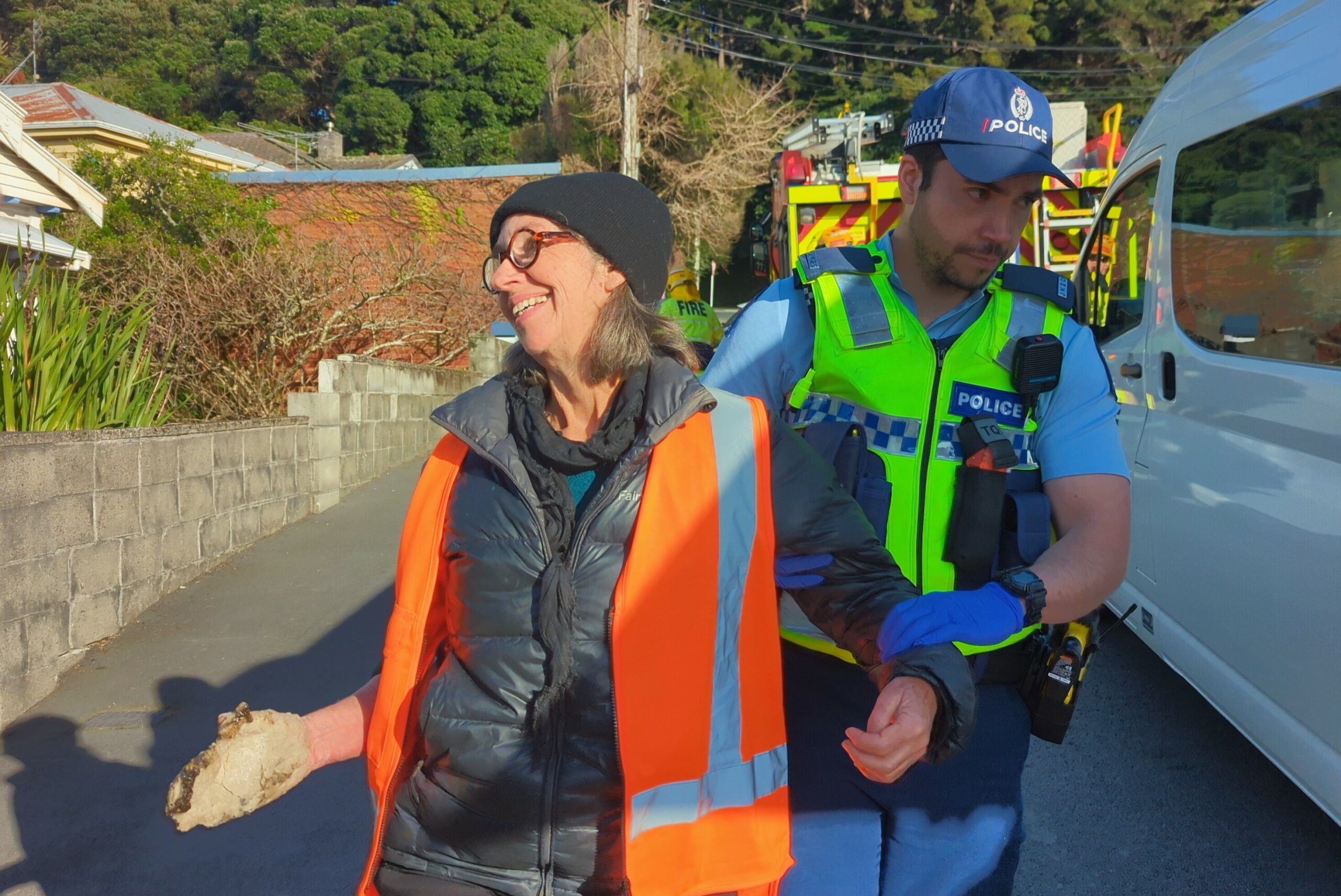 Rosemary Penwarden is led away by police after gluing her hand to a road in New Zealand to stop traffic as part of a protest by Restore Passenger Rail in August 2023. Credit: Photo Courtesy Restore Passenger Rail