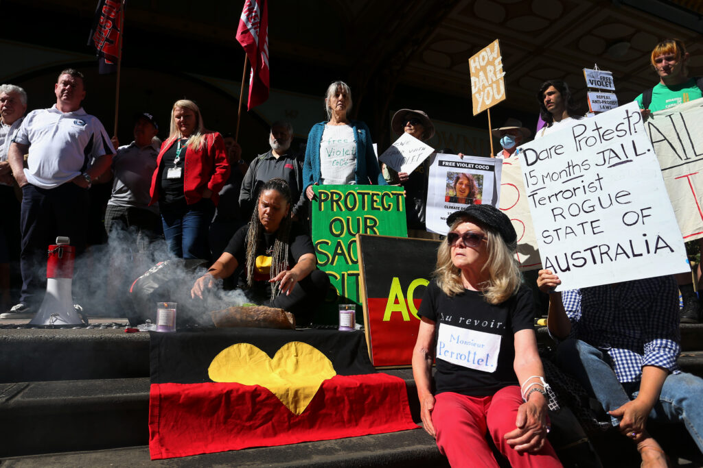 Widjabul-Wyabul woman Cindy Roberts performs a smoking ceremony alongside activists at a rally at Violet Coco's bail hearing at the Downing Centre Courts on December 13, 2022 in Sydney, Australia. Coco was sentenced to serve 15 months for charges related to a climate protest she participated in which disrupted traffic on Sydney's harbour bridge. Premier Dominic Perrottet and other political leaders have characterised the sentence as "pleasing", however civil society groups, including Human Rights Watch, have heavily criticized it, calling it a slippery slope to jail peaceful protesters in New South Wales. Credit: Lisa Maree Williams/Getty Images