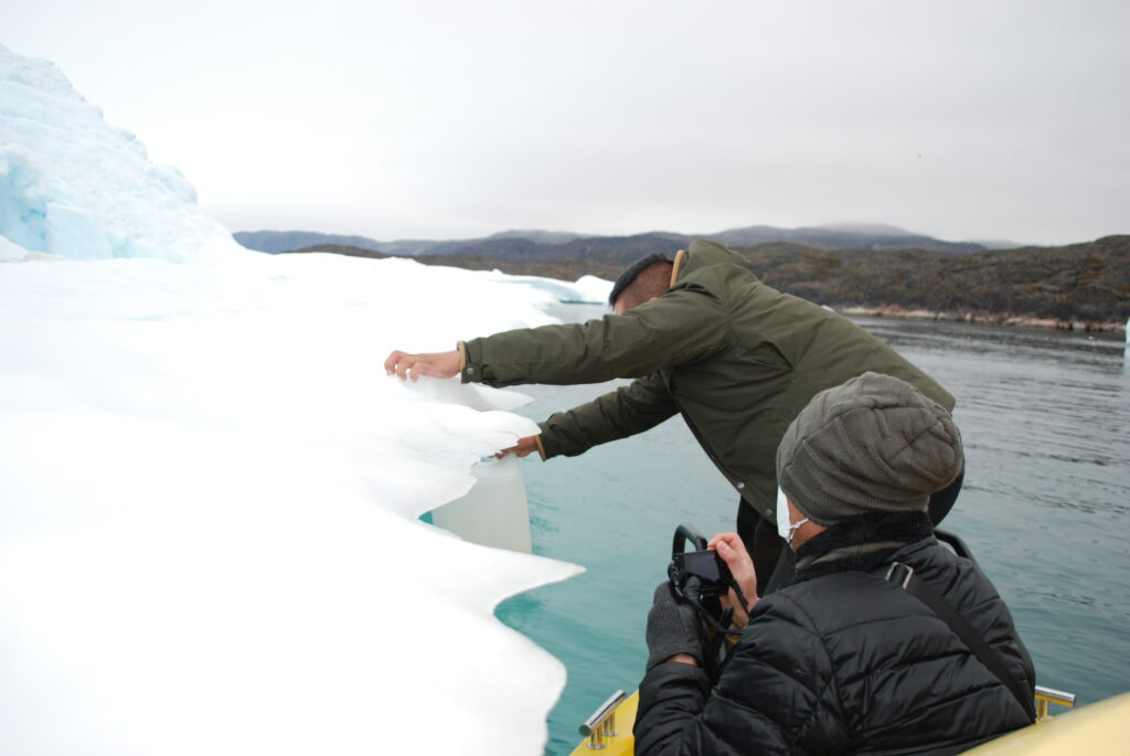 A local boat tour guide collects water from the Ilulissat ice sheet during a whale watching tour on Sept. 6, 2022. Credit: Natasha Jessen-Petersen
