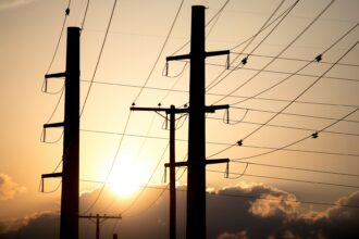 The sun sets behind power transmission lines, part of the Electric Reliability Council of Texas (ERCOT), the state's power grid. Credit: Nick Wagner/Xinhua via Getty Images.