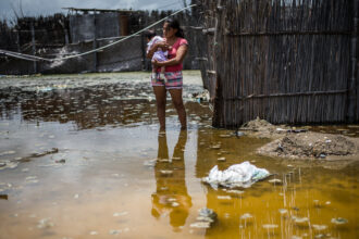 A woman and her baby stand in a flooded street, in the province of La Union in Piura, northern Peru, on March 25, 2017. Credit: Ernesto Benavides/AFP via Getty Images