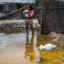 A woman and her baby stand in a flooded street, in the province of La Union in Piura, northern Peru, on March 25, 2017. Credit: Ernesto Benavides/AFP via Getty Images