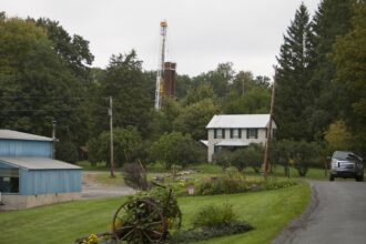 A car drives by a home with a nearby derrick drilling for natural gas near Calvert, Pennsylvania. Credit: Robert Nickelsberg/Getty Images