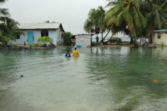 Local residents wade through flooding caused by high ocean tides in Majuro Atoll, the capital of the Marshall Islands, on February 20, 2011, with a warning of worse to come because of rising sea levels.