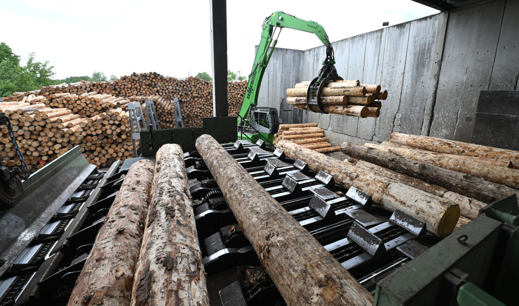 An excavator loads logs used for wood pellets at a sawmill.