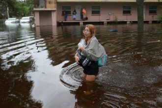 In Tarpon Springs, Florida, Makatla Richter wades through flood waters after having to evacuate her home when the flood waters from Hurricane Idalia inundated it on Wednesday. Credit: Photo by Joe Raedle/Getty Images.