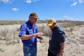 John Allaire (left), a retired oil and gas environmental manager, consulted with James Hiatt, the southwest Louisiana coordinator of the Louisiana Bucket Brigade, in March on Allaire's Cameron Parish, Louisiana property. Venture Global's Calcasieu Pass LNG export terminal is in the background. The proposed Commonwealth LNG terminal would be constructed nearby. Credit: James Bruggers