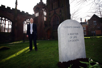 Climatologist and NASA scientist James Hansen poses next to a mock grave stone declaring 'Climate change-a matter of life or death' outside the ruins of Coventry Cathedral on March 19, 2009 in Coventry, England. The symobolic head stone is the first stage of a climate change campaign action day. Credit: Christopher Furlong/Getty Images