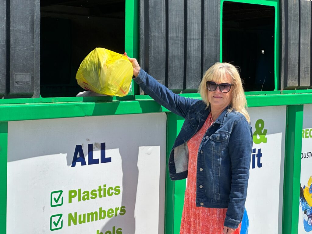 Jan Dell, founder of The Last Beach Cleanup and a chemical engineer, places a plastic bag with an Apple AirTag tracker in a recycling container in the Kingwood community of Houston. Credit: James Bruggers/Inside Climate News