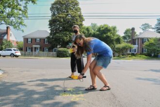 Beyond Methane RVA volunteer Megan Stueber measures for gas leaks while Lee Williams hands out informative flyers on methane leaks on Grove Avenue on June 9, 2023. Credit: Ananya Chetia