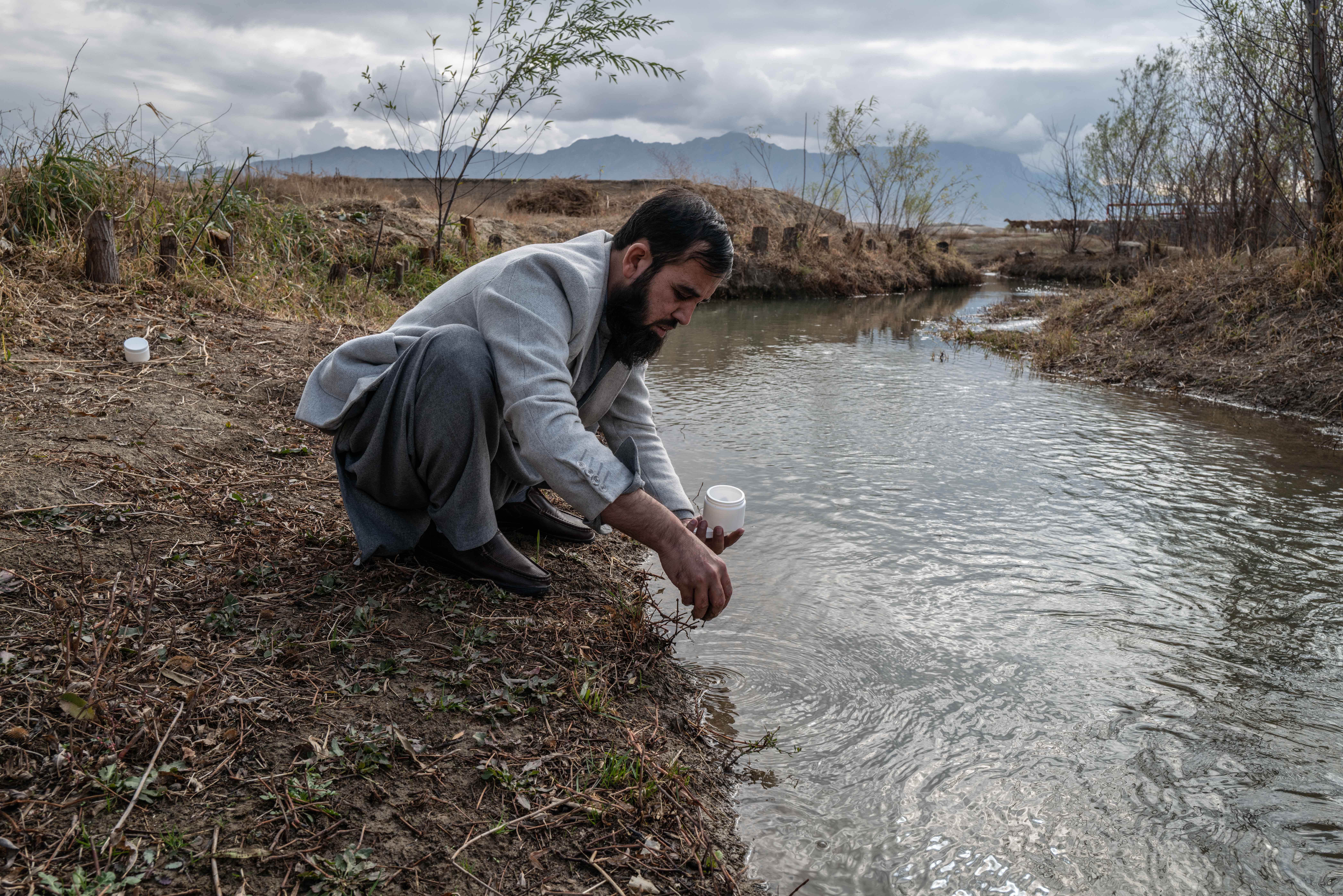 An Afghan scientist gathers water and soil samples at a water outflow from Bagram Airfield, formerly America's largest military base in Afghanistan. Credit: Kern Hendricks