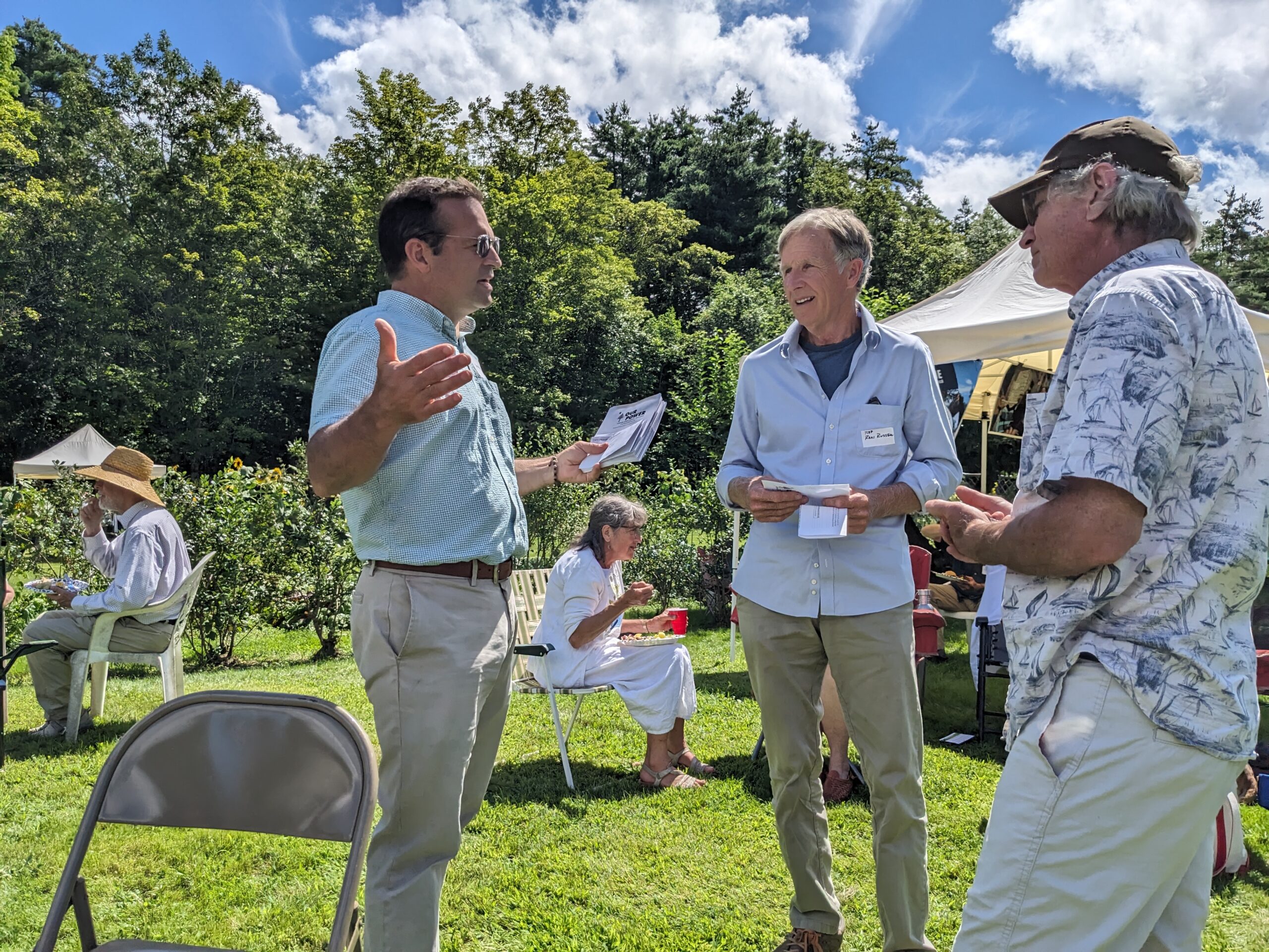 Seth Berry, left, an author of the Pine Tree Power proposal and a former Democratic state representative, answers questions from potential voters at a gathering of climate activists at a home in Winslow, Maine, in August. Credit: Annie Ropeik