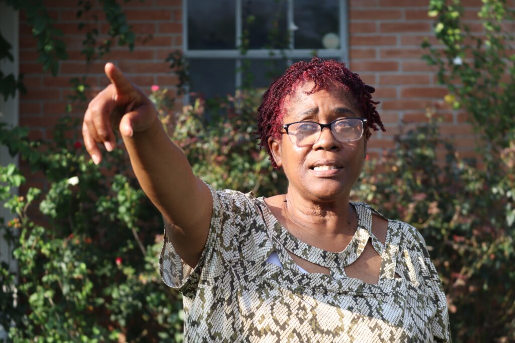 Shirley Williams can see furnaces of an ExxonMobil chemical plant from beyond the wooden fence in her backyard in Baytown, Texas. She said odors can make it unbearable outside. Credit: James Bruggers/Inside Climate News