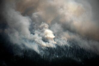 This aerial picture taken from an airplane on July 27, 2021, shows the smoke rising from a forest fire outside the village of Berdigestyakh, in the republic of Sakha, Siberia. Credit: Dimitar Dilkoff/AFP via Getty Images