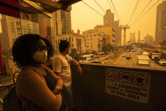 People wear masks as they wait for the tramway to Roosevelt Island as smoke from Canadian wildfires casts a haze over the area on June 7, 2023 in New York City. Credit: Eduardo Munoz Alvarez/Getty Images