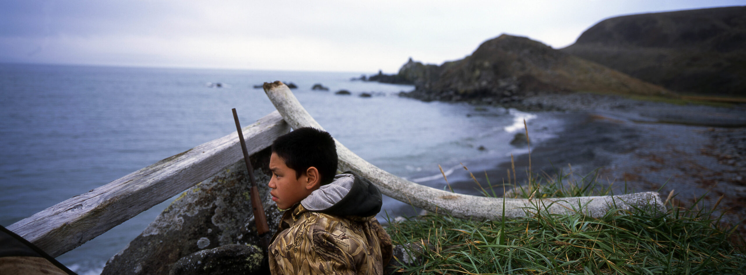 Steven James, 12, waits to hunt geese on St. Lawrence Island, in Alaska, sitting hidden behind a wood bar and a whale bone. Credit: Ann Johansson/Corbis via Getty Images.