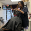 Yakini Horn, owner of Yaya’s Natural Hair Boutique in Atlanta, rolled sections of Akeyla Peele-Tembong’s hair in her hands during a styling visit on Feb. 20, 2023. Horn was creating “starter locs,” the early stage of a natural hairstyle that will take months to root. Credit: Victoria St. Martin